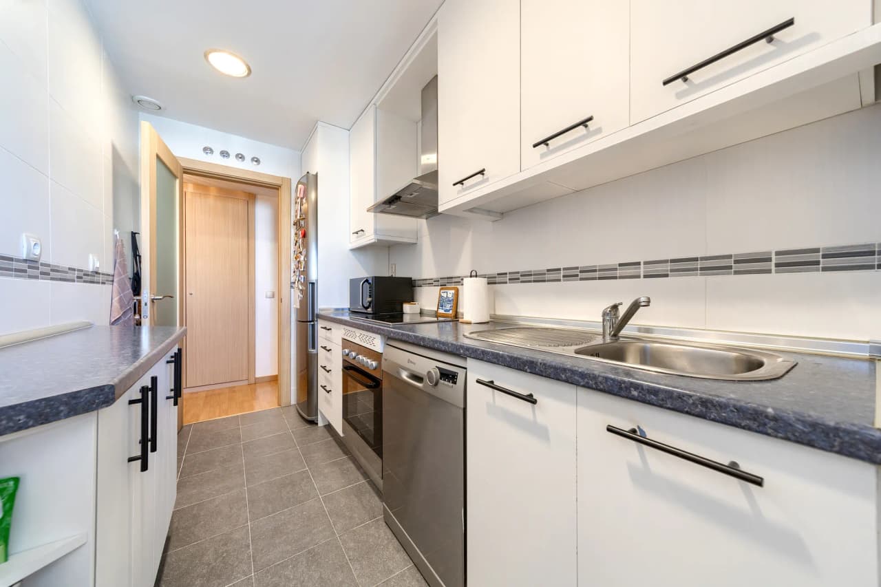 Cocina independiente amueblada, con placa, horno, campana y fregadero bajo la ventana
