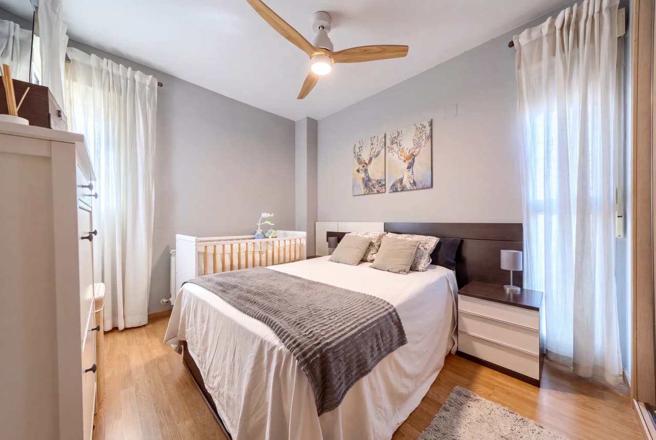 Dormitorio principal con cama de matrimonio, ventilador de techo y ventana