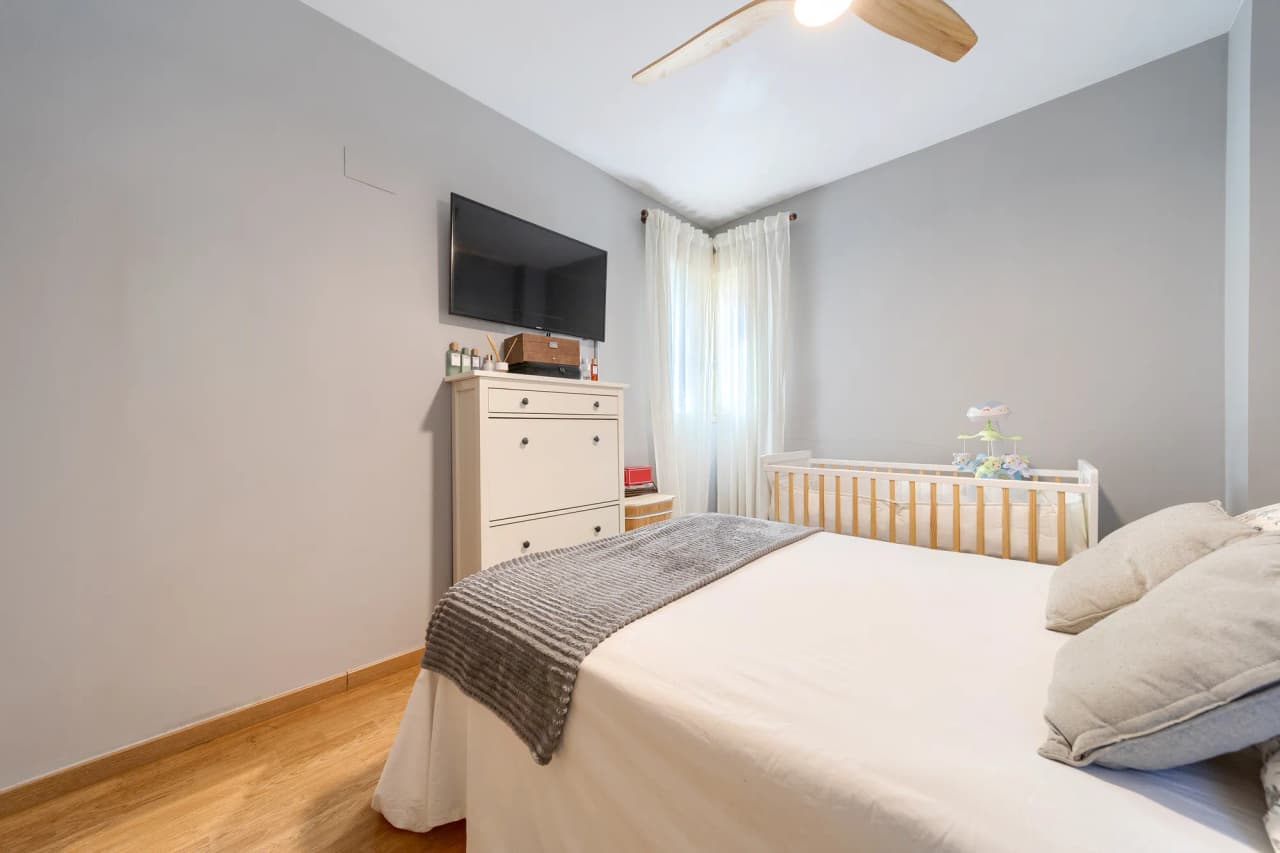 Dormitorio principal con televisión y cómoda frente a la cama