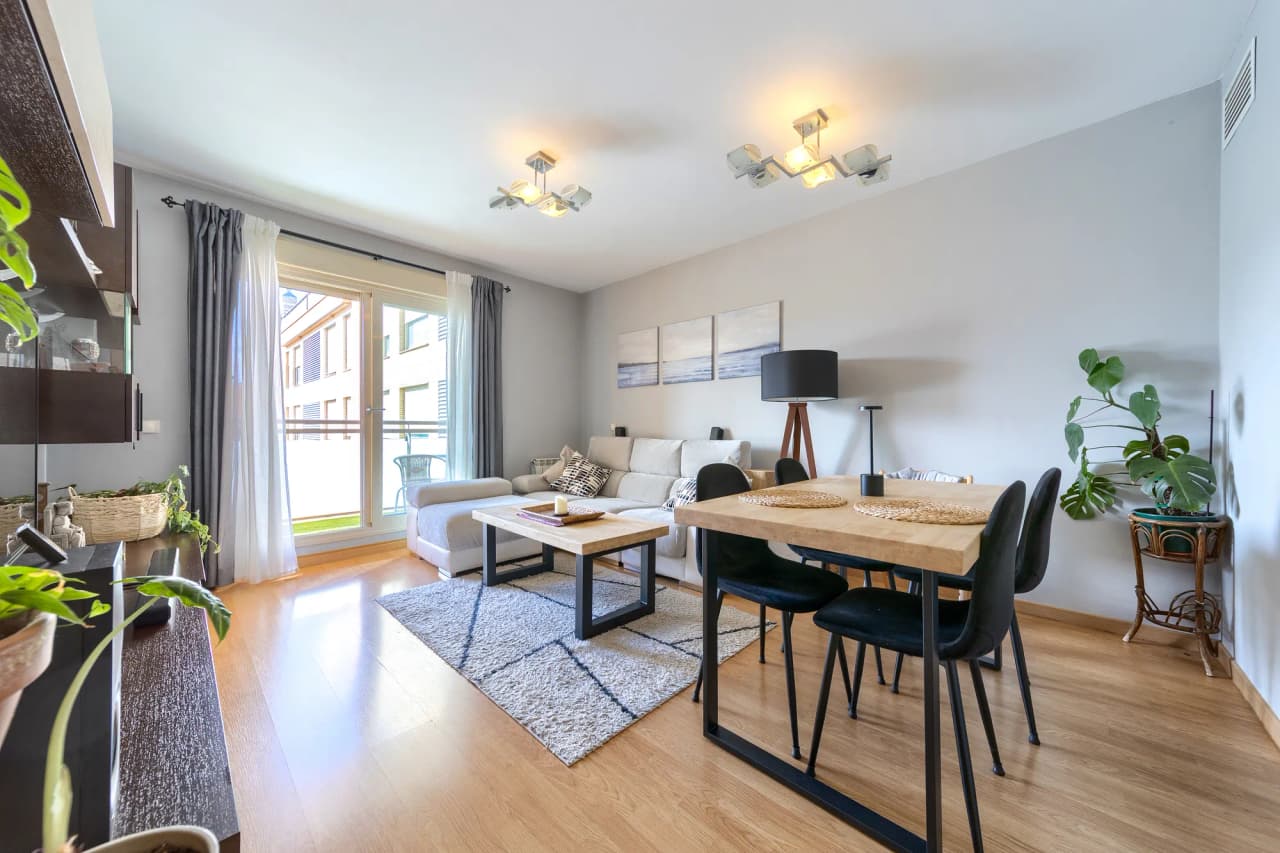 Salón comedor con sofá, mesa de comedor y salida acristalada a la terraza