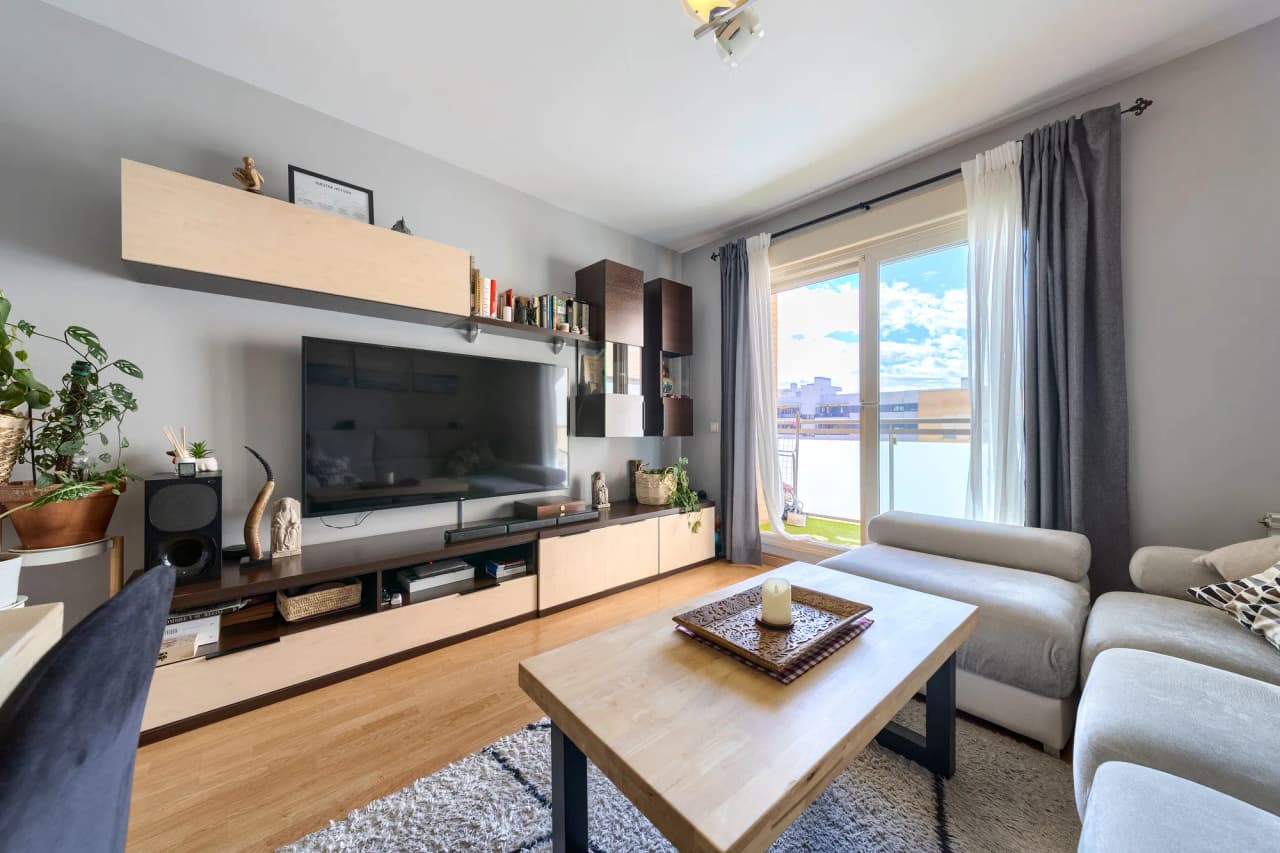 Zona de estar del salón con mueble de televisión y ventanal a la terraza