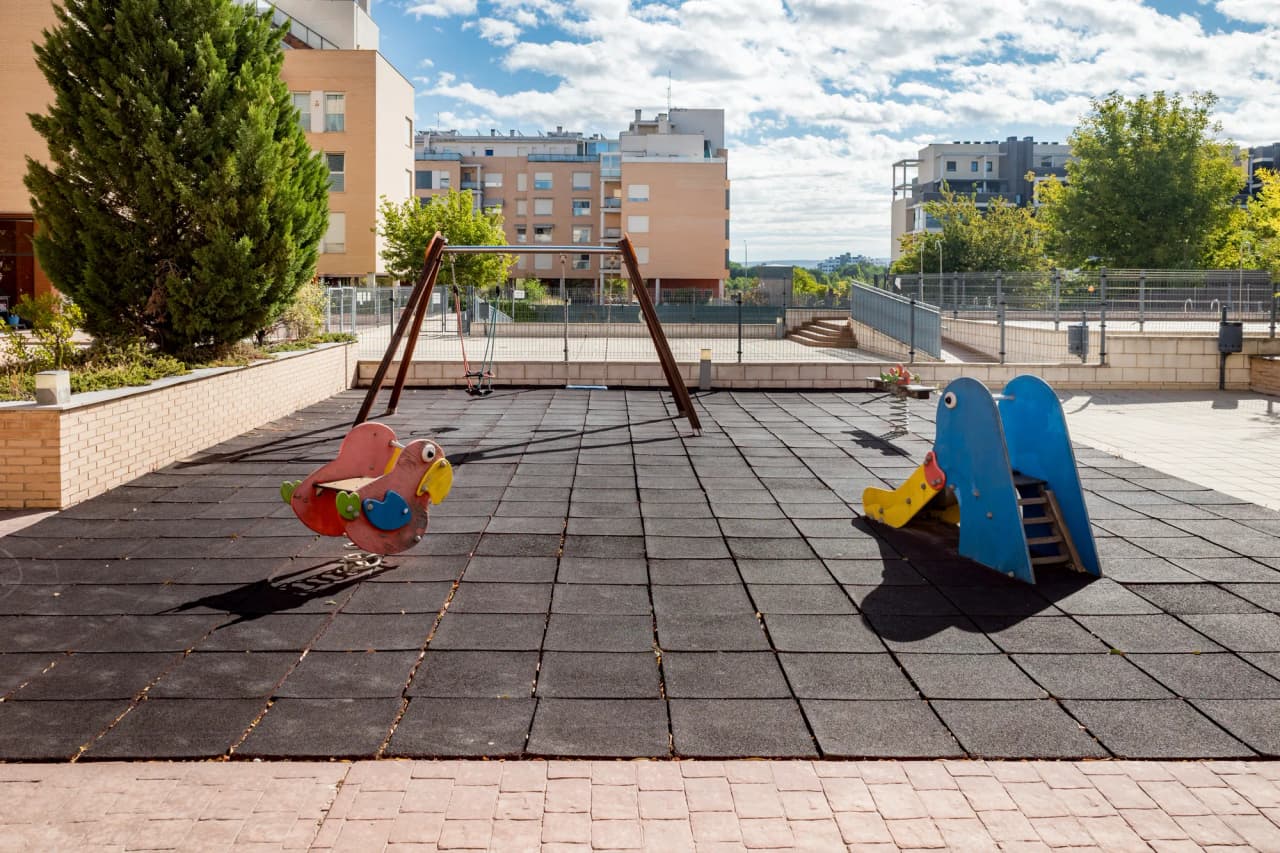 Zona de juegos infantiles con suelo amortiguado, entre los bloques