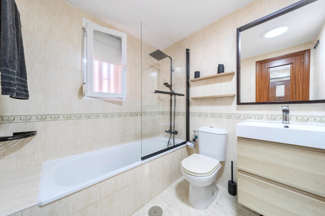 Baño completo con bañera, mampara y mueble de lavabo
