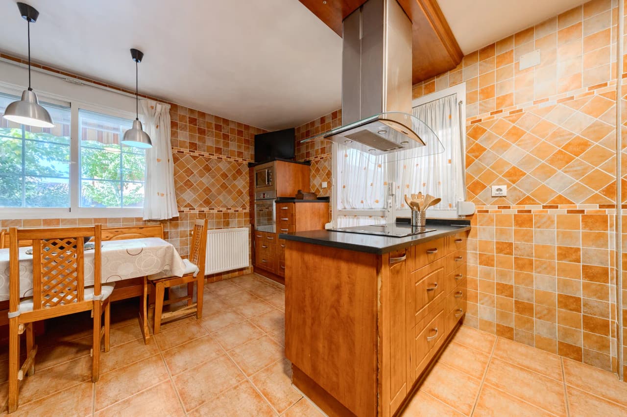 Cocina con isla y campana, y el office con mesa junto a la ventana