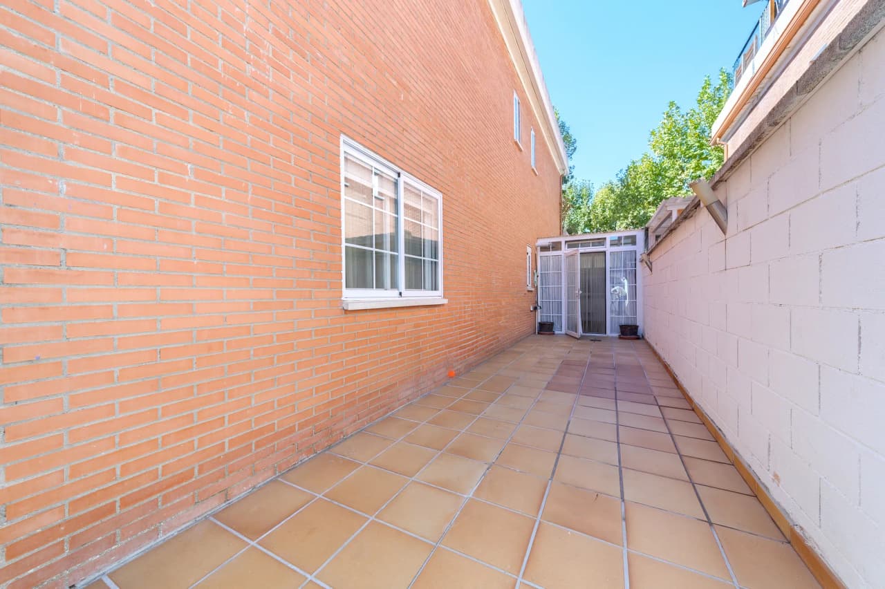 Pasillo lateral pavimentado entre la casa y el muro de la parcela